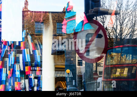 Composizione astratta realizzata dalle riflessioni di un no a destra segno, bus, edifici e colori luminosi nella vetrina di un negozio nel villaggio di Highgate, London, Regno Unito Foto Stock