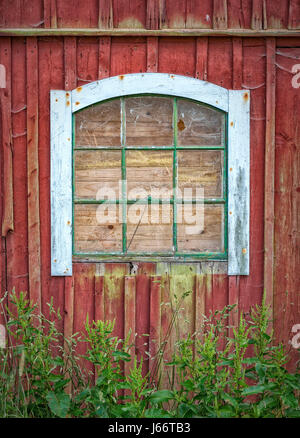Un intavolato vetro rotto di un classico rosso campagna fienile. Foto Stock