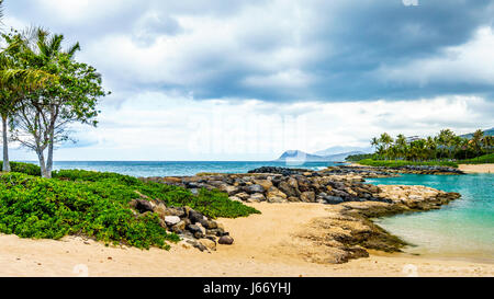 Alberi di palma nel vento al Ko Olina lagune sotto il cielo nuvoloso presso le lagune di Ko Olina sulla costa ovest dell'isola hawaiana di Oahu Foto Stock