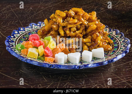 Chak-chak oriental dolci, frutta secca e figurato lo zucchero in una tradizionale orientale piastra su un vecchio incrinato superficie verniciata Foto Stock