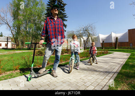 Papà con bambini in scooter Foto Stock