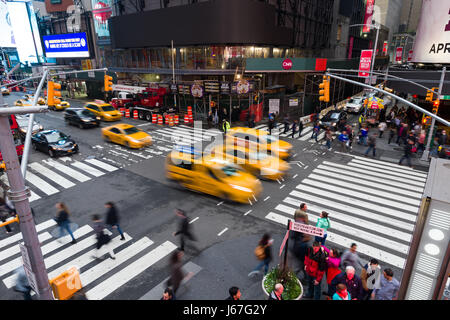 Giallo Taxi guidando attraverso Times Square incrocio con i pedoni in attesa, New York Foto Stock