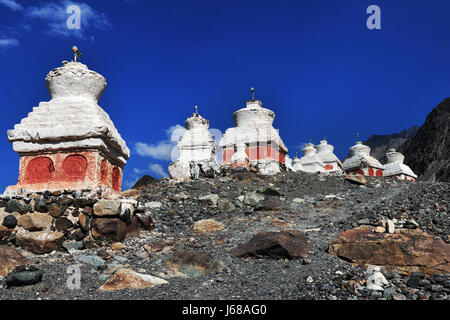 Molti antichi stupa buddisti sul ripido pendio della montagna sotto un luminoso cielo blu: la stupa sono impostate su una collina sassosa, di seguito sono riportati i modelli di rosso, th Foto Stock