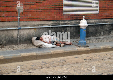 Un senzatetto giace addormentato sul marciapiede fuori della trafficata Stazione ferroviaria in Kolkata, India il 10 febbraio 2016. Foto Stock