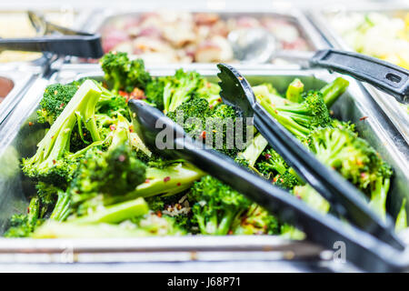 Macro closeup di broccoli cotti al vapore con peperoncino rosso in buffet con pinze Foto Stock