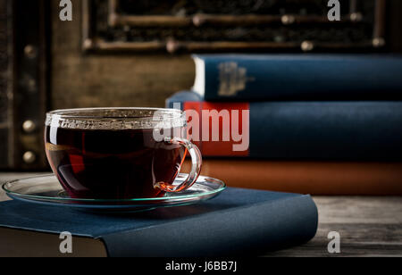 Tazza di tè con libri antichi in stile retrò su sfondo di legno con spazio di copia Foto Stock