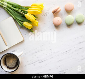 Vista superiore del notebook, caffè, macarons e tulipani su Sfondo marmo Foto Stock