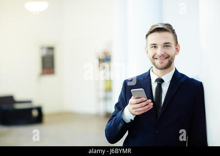 Felice giovane con smartphone tuta da indossare Foto Stock