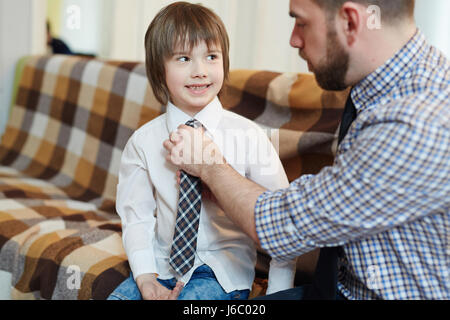 L'uomo aiutando il suo figlio con cravatta mentre vestirsi Foto Stock