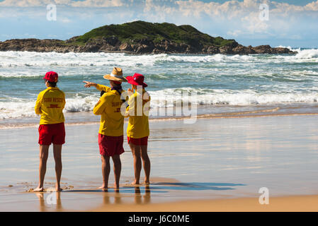 Tre bagnini a Coffs Harbour Beach con poco Muttonbird Island in vista. NSW. Australia Foto Stock