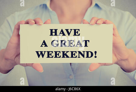Closeup imprenditrice mani carta bianca segno con avere un grande fine settimana messaggio di testo isolato sul muro grigio office background. Retrò instagram st Foto Stock