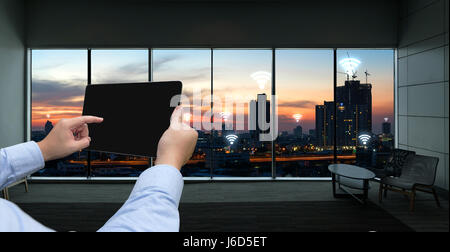 Internet delle cose , iot di rete e collegare il concetto. Imprenditore mano azienda compressa nero con city sunset lo sfondo e le icone di wifi Foto Stock
