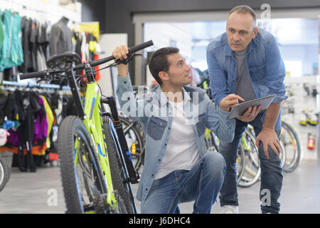 Bike Shop assistente aiutando il cliente a bike store Foto Stock