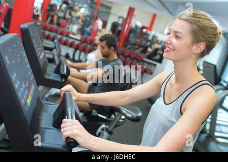 Montare la bionda utilizzando la fase macchina in palestra Foto Stock