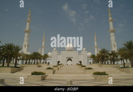 Scalinata con vista sul cielo blu con palme che si innalzano verso minareti e cupole sopra l'ingresso orientale della grande Moschea dello Sceicco Zayed, Abu Dhabi, Emirati Arabi Uniti Foto Stock