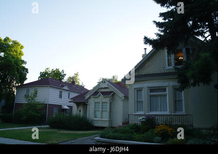 Vista all'ombra del cielo blu pomeridiano di tre case con prati frontali, giardini e pini, Canyon Road presso la 4th Avenue, Salt Lake City, Utah, USA Foto Stock