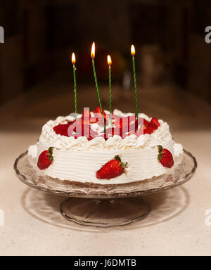 Torta di compleanno con candele, luci luminose bokeh di fondo sul tavolo Foto Stock