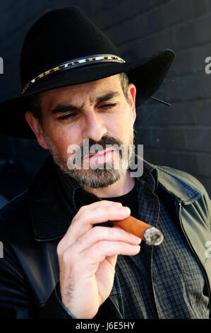 Il sigaro hat barba dura da cowboy fumatore odore di fumo uomo fumatori ragazzo uomo uomo Foto Stock