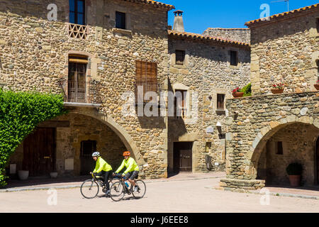 Due cicloturisti cavalcare le loro biciclette titanio in Plaça Jaume I, a Monells, provincia di Girona, Spagna. Foto Stock