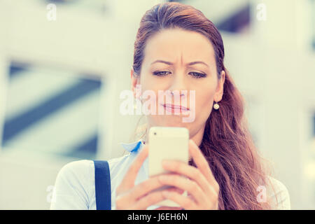 Primo piano laterale verticale del profilo sconvolto triste scettico infelice donna gravi parlando texting sul telefono orinato con conversazione isolato sullo sfondo della città Foto Stock