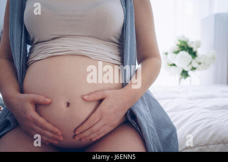 Close up della donna incinta toccando il suo ventre con le mani Foto Stock