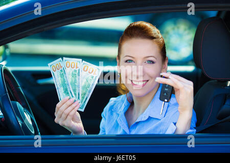 Closeup ritratto sorridenti attraente donna seduta nella sua nuova auto nera che mostra i tasti, tenendo le fatture del dollaro isolato cittadino concessionaria molto ba Foto Stock