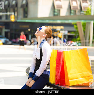 Donna Shopping in New York City. Bella felice, sorridente estate shopper con giallo shopping bags rilassante sulla giornata di sole al di fuori. Emozioni positive, f Foto Stock