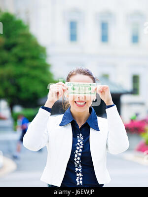 Closeup ritratto tranquilla politico corrotto in Washington DC, donna holding che copre la sua gli occhi con le fatture del dollaro isolati dal Capitol Building sfondo. Hu Foto Stock
