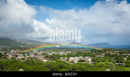 Un luminoso e vibrante ultra-bassa Hawaiian rainbow sulla lussureggiante vegetazione verde di un quartiere residenziale di Honolulu. Foto Stock