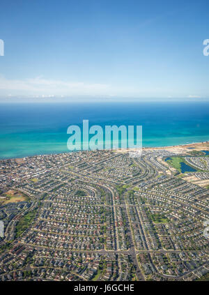 Veduta aerea dei sobborghi di Hawaiian, Mostra righe e righe di case si trova vicino le splendide acque blu della spiaggia di Eva su Oahu il lato sottovento. Foto Stock