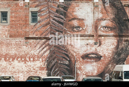 Arte di strada - una grande immagine di una giovane donna di fronte sul lato di un edificio in Christchurch, sull'Isola Sud della Nuova Zelanda Foto Stock