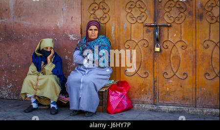 Due donne sedute fuori dalla porta chiusa a chiave a Marrakech, in Marocco Foto Stock