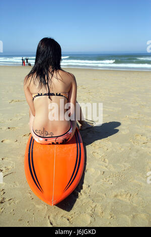 Donna mare spiaggia La spiaggia mare retro jersey surfer mettere seduta siedono giovani Foto Stock