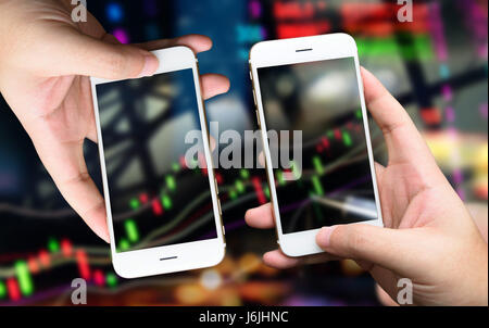 Fintech Concetto di immagine. Mano che regge due telefoni smart comprare e vendere azioni su schermo mobile. stock market concetto sfondo immagine Foto Stock