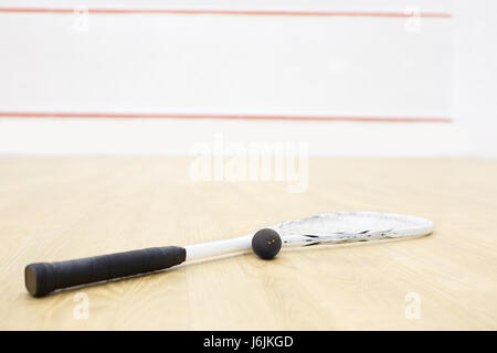 Racchette da squash e la sfera. Raquetball apparecchiature sulla corte e parete con linee rosse sullo sfondo. Foto con il fuoco selettivo Foto Stock