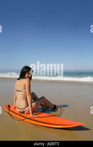 Donna mare spiaggia La spiaggia mare vista frontale jersey surfer mettere seduta sit Foto Stock