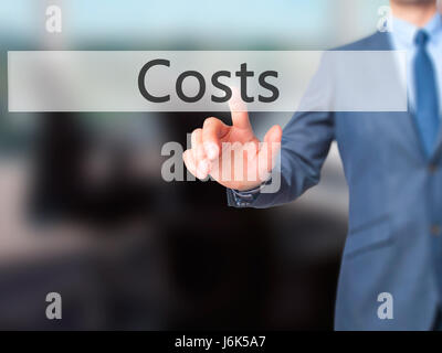 Costi - Imprenditore mano premere il pulsante sulla schermata virtuale di interfaccia. Business, concetto tecnologico. Stock Photo Foto Stock