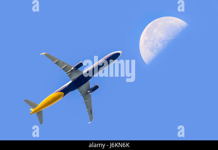 Fly me la luna. Passeggero aereo jet vola alto contro il cielo blu con la luna in distanza. Il viaggio in aereo. Volare sopra le nuvole. Foto Stock