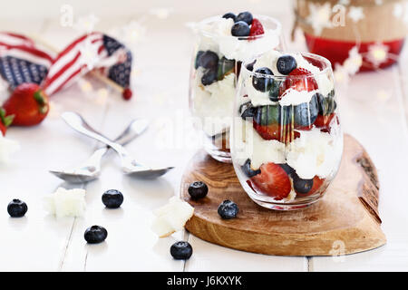 Inezia realizzato con mirtilli, fragole e panna montata e a forma di stella ciambellone seduti su un quarto di luglio del tavolo da picnic. Profondità di campo Foto Stock