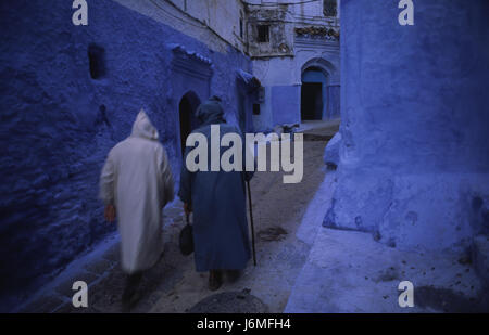 17.11.2010, Chefchaouen, Marocco, Africa - La gente del posto a piedi attraverso il labirinto di vicoli e il passato di colore bianco-blu colorate facciate di casa nella medina. Foto Stock