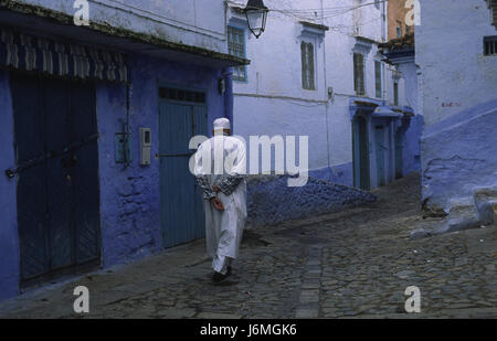 18.11.2010, Chefchaouen, Marocco, Africa - un uomo cammina attraverso il labirinto di vicoli e il passato di colore bianco-blu colorate facciate di casa nella medina. Foto Stock