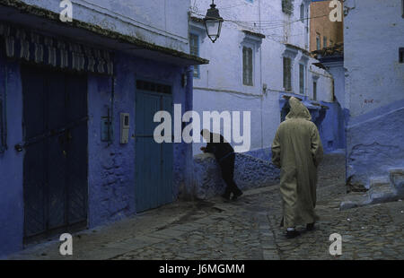 18.11.2010, Chefchaouen, Marocco, Africa - La gente del posto a piedi attraverso il labirinto di vicoli e il passato di colore bianco-blu colorate facciate di casa nella medina. Foto Stock