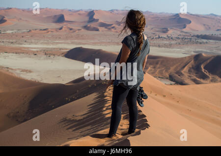 Donna in piedi su Big Daddy dune di sabbia che si affaccia sul paesaggio del deserto, Sossusvlei, Namibia Foto Stock