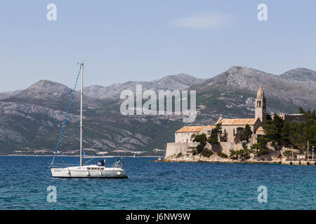 Uno yacht nella foto al largo della costa della isola di Lopud nel sud della Croazia. Il monastero francescano può essere visto sulla fine della passeggiata del dista Foto Stock