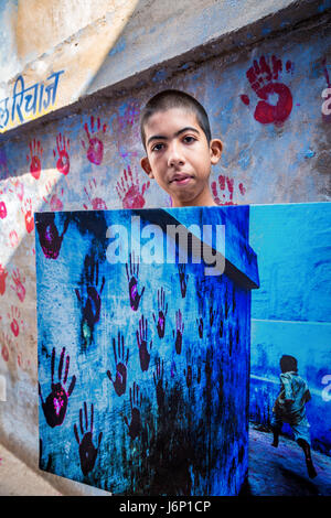 Ragazzo con una stampa di Steve Mccurry's photo - Boy in esecuzione attraverso il vicolo, Jodhpur, Rajasthan, India Foto Stock