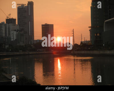 I "tramonti a Makati e Mandaluyong City" catturano la bellezza delle vedute del tramonto urbano su queste due vivaci città della metropolitana di Manila. L'immagine mostra i vibranti paesaggi urbani con il sole che tramonta sullo skyline. Foto Stock