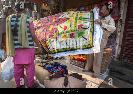 Delhi, India - 10 novembre 2012 - Due donne acquistando un colorato tovaglia da un venditore ambulante, un modo molto popolare di trovare un affare. Foto Stock