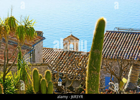 I vecchi tetti in piastrella di Eze con il piccolo campanile della cappella di Santa Croce dei penitenti bianchi e la superficie calma del mare Mediterraneo sulla ba Foto Stock