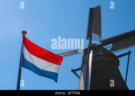 Famoso vecchio mulino a vento olandese e bandiera dei Paesi Bassi, Zaanse Schans, Paesi Bassi, l'Europa. In tipico stile olandese mulino. paesaggio rurale in Olanda. Simbolo di t Foto Stock