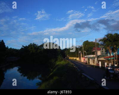 Questa immagine mostra uno splendido tramonto sul ponte di San Miguel, che attraversa il fiume San Juan a Poblacion, Bulacan. La tranquilla scena cattura la bellezza del fiume al tramonto, mettendo in risalto gli ambienti naturali e costruiti. Foto Stock